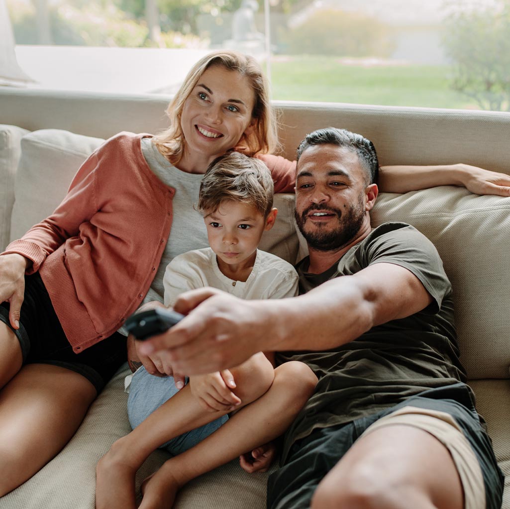 Family sitting on a couch enjoying TV