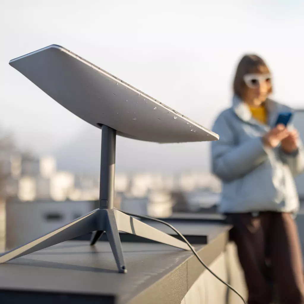 Starlink antenna on a Perth rooftop and a woman using the Starlink app on her phone